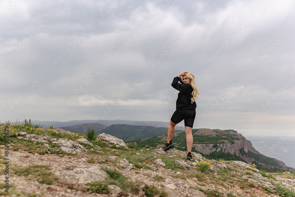 Obraz premium A woman stands on a rocky hillside, looking out over the landscape
