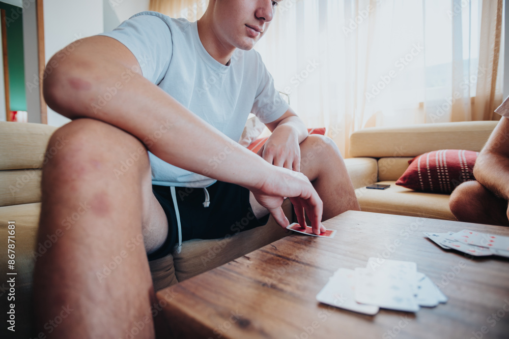 Young men enjoying their leisure time by playing cards in a cozy living room, building companionship.