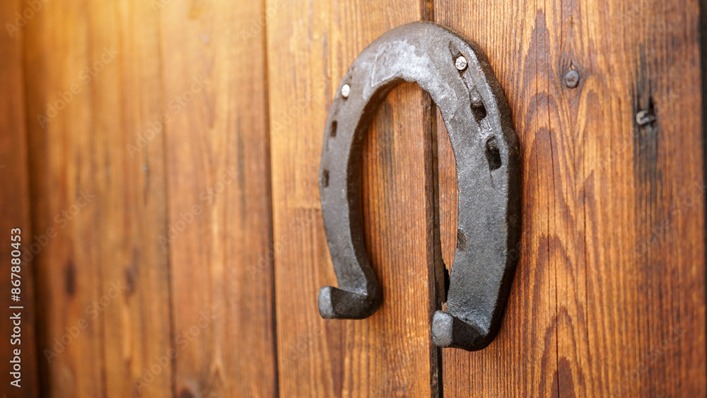 A horseshoe for good luck hanging on a wooden door. Symbol for luck and fortune. An iron lucky horseshoe - a talisman superstition for luck. A horseshoe for good luck hanging on a wooden door. Symbol for luck and fortune. An iron lucky horseshoe - a talisman superstition for luck.