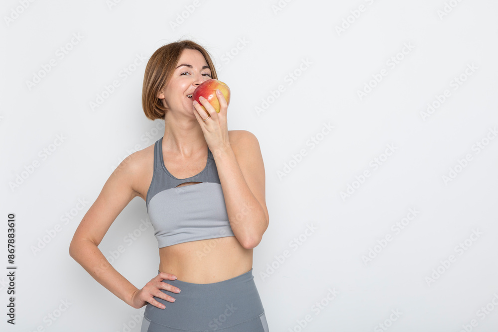 Close up portrait of pretty woman in sportswear holding apple isolated on white background. Healthy lifestyle concept Close up portrait of pretty woman in sportswear holding apple isolated on white background. Healthy lifestyle concept