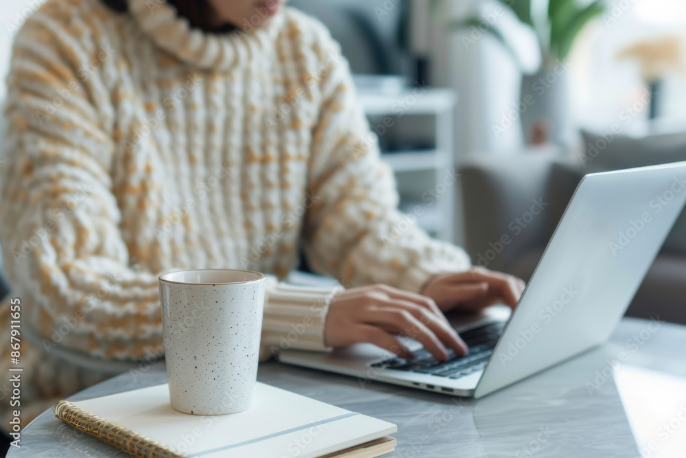 Person working on laptop at desk with coffee cup and stationery in modern office. Ideal for business, productivity, and remote work themes. Person working on laptop at desk with coffee cup and stationery in modern office. Ideal for business, productivity, and remote work themes.