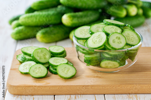 chopped fresh cucumbers slices in a clear glass bowl on a light table.