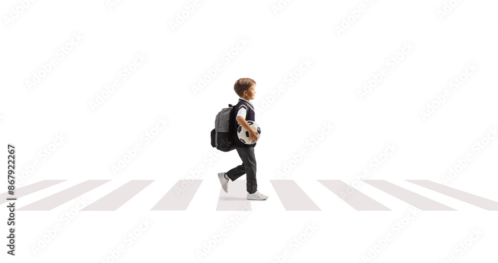 Full length profile shot of a schoolboy carrying a football and walking at a pedestrian crossing Full length profile shot of a schoolboy carrying a football and walking at a pedestrian crossing