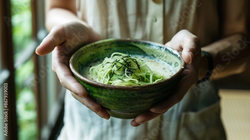 Close-up of a person holding a bowl of fresh green vegetables, emphasizing a healthy, plant-based diet in a natural setting.