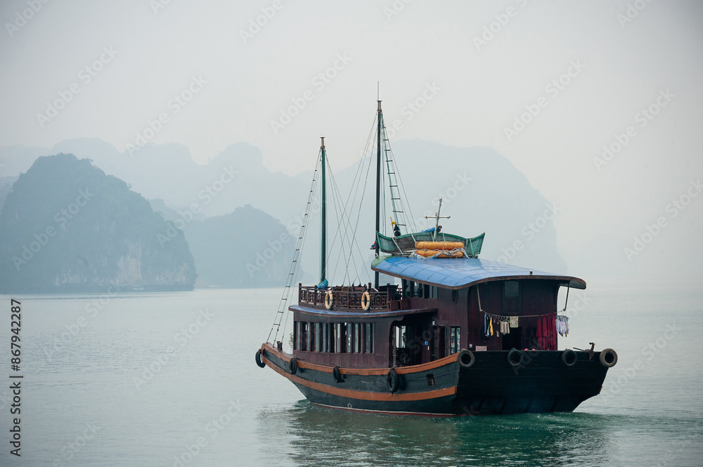 Junk boats in Halong Bay amongst the islets surround by the sea fog in Vietnam stunning views of UNESCO World Heritage site Junk boats in Halong Bay amongst the islets surround by the sea fog in Vietnam stunning views of UNESCO World Heritage site