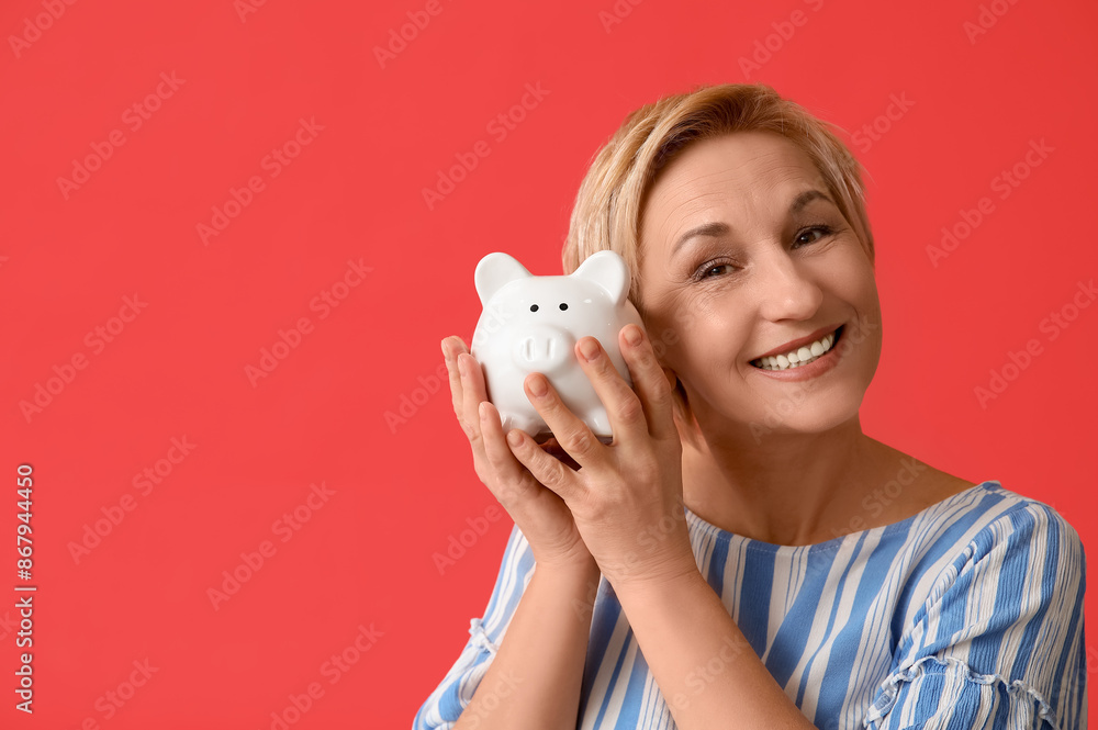 Happy mature woman with piggy bank on red background Happy mature woman with piggy bank on red background