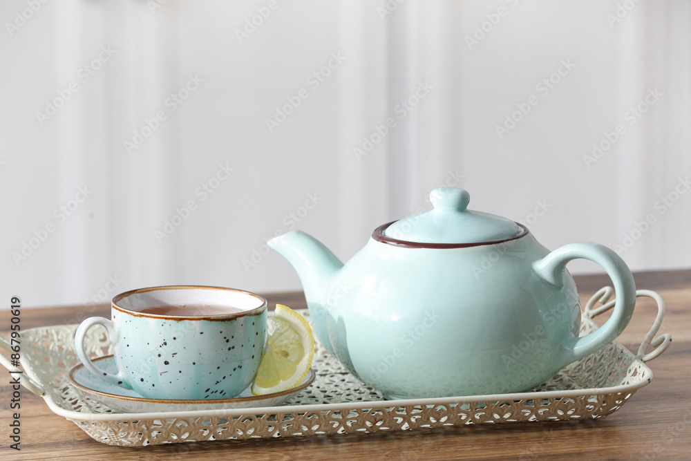 Tray with teapot, cup of tea and lemon slice on wooden table in kitchen Tray with teapot, cup of tea and lemon slice on wooden table in kitchen