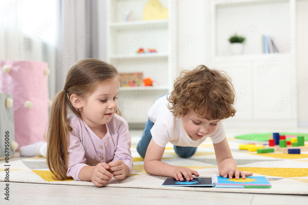 Cute little children reading book on floor in kindergarten Cute little children reading book on floor in kindergarten