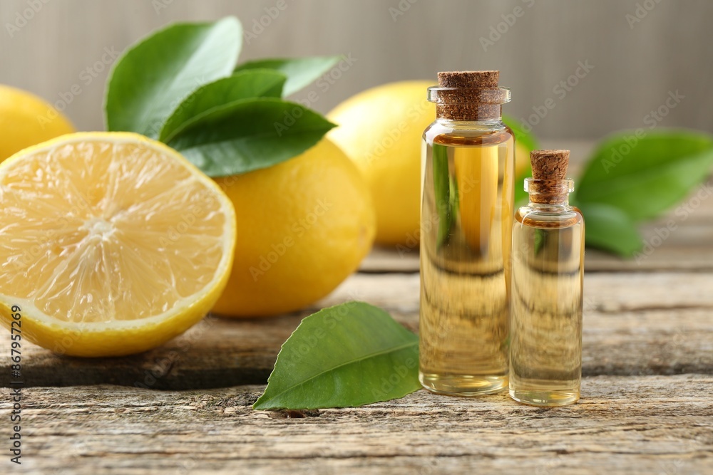 Essential oils in bottles, lemons and green leaves on wooden table Essential oils in bottles, lemons and green leaves on wooden table