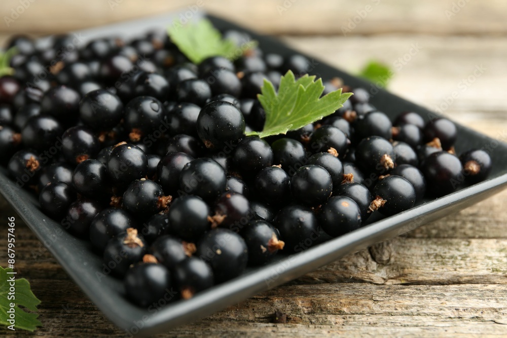 Ripe black currants and leaves on wooden table, closeup Ripe black currants and leaves on wooden table, closeup