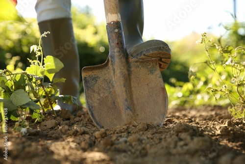 Farmer digging soil with shovel on sunny day, closeup