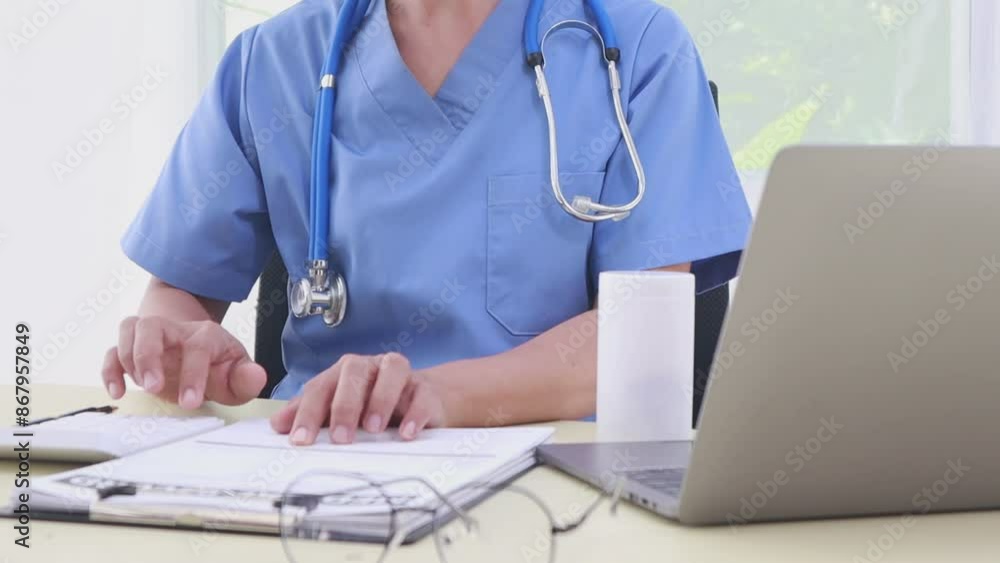 A middle-aged Asian female doctor and nurse work at a desk, providing medical advice through online consultation or tele-consultation services. A middle-aged Asian female doctor and nurse work at a desk, providing medical advice through online consultation or tele-consultation services.