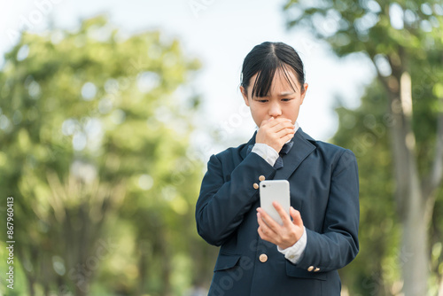 スマホを見て嫌がる・驚く・びっくりする制服姿・ブレザー姿の中学生・高校生の女の子 