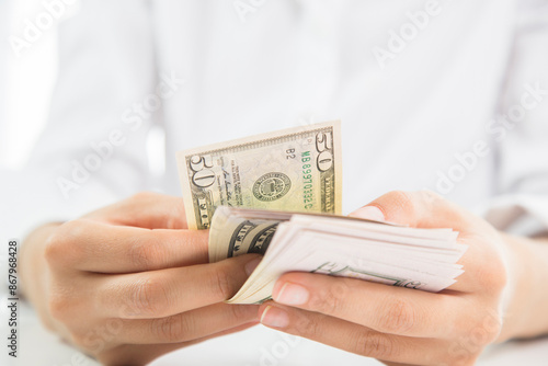 Close up of someone hands holding and counting American dollar banknotes in her hand.