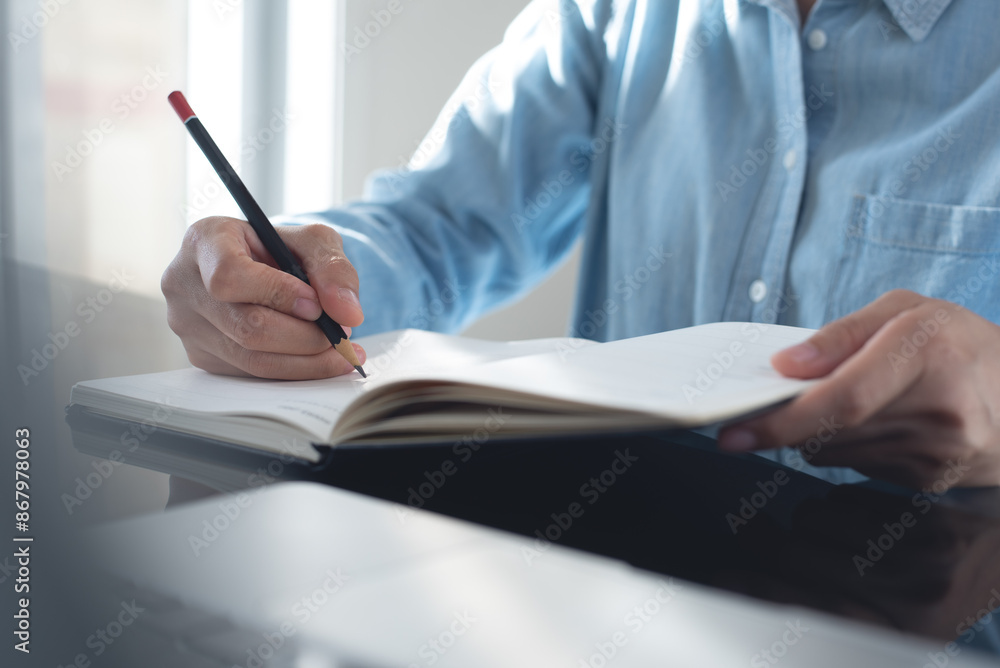 Business woman hand writing with pencil planning event on notebook. Job schedule, event planning, to do list and reminder, E-learning. Woman working on laptop and taking note on office desk, close up Business woman hand writing with pencil planning event on notebook. Job schedule, event planning, to do list and reminder, E-learning. Woman working on laptop and taking note on office desk, close up
