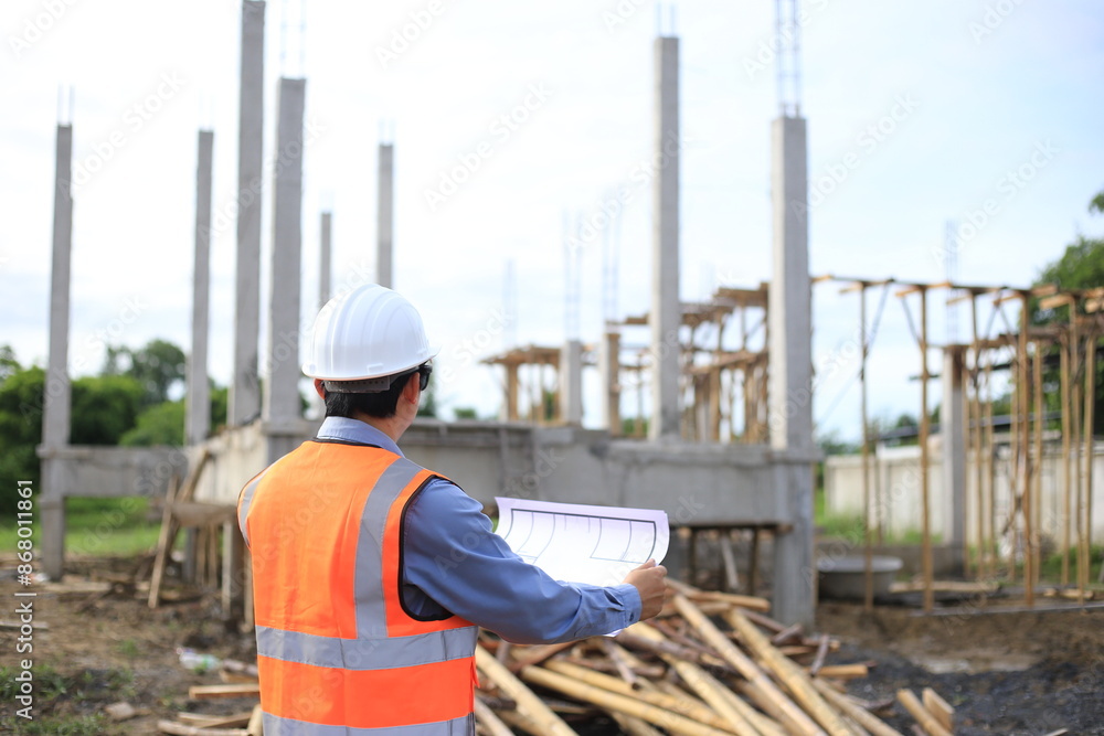 Young professional engineer in hat and blueprint paper is working...At the house construction site. Motivation: success, career growth. achieving goals Young professional engineer in hat and blueprint paper is working...At the house construction site. Motivation: success, career growth. achieving goals