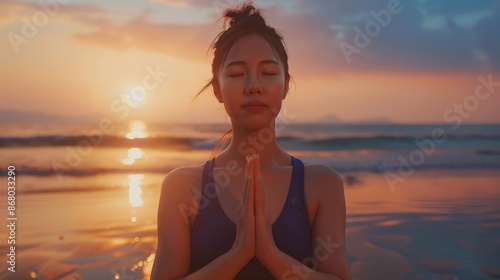 Woman meditates on a beach at sunset