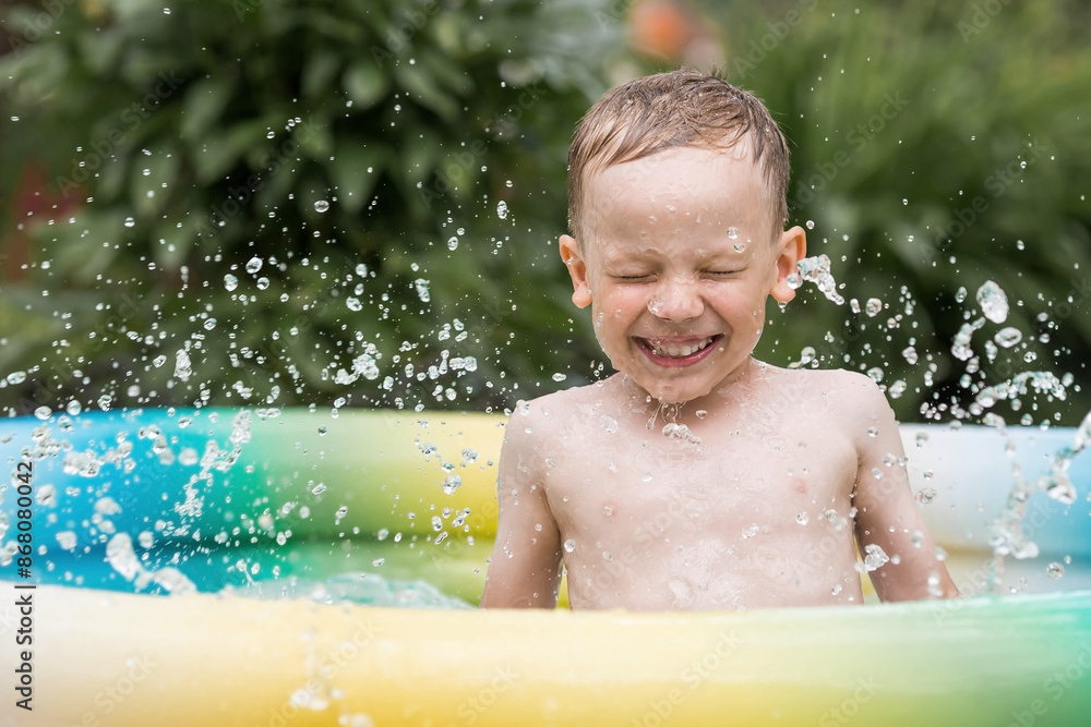 It's a hot day. A cute boy is swimming and splashing in the pool. A happy little boy smiles at the camera. Splashes of water are flying in all directions. The concept of summer holidays with children. It's a hot day. A cute boy is swimming and splashing in the pool. A happy little boy smiles at the camera. Splashes of water are flying in all directions. The concept of summer holidays with children.