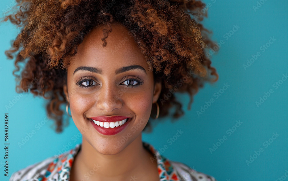 A trans woman with North African features and curly hair smiles at the camera against a bright blue background A trans woman with North African features and curly hair smiles at the camera against a bright blue background