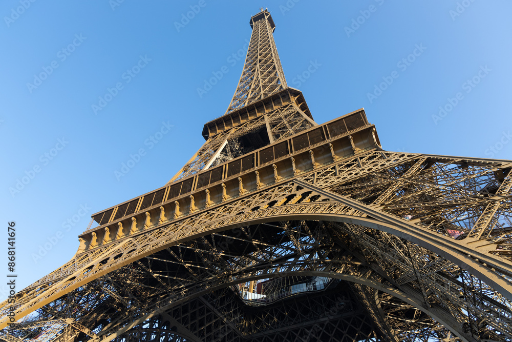 Fototapeta premium Base structure of Eiffel tower in Paris, France. Early golden morning light