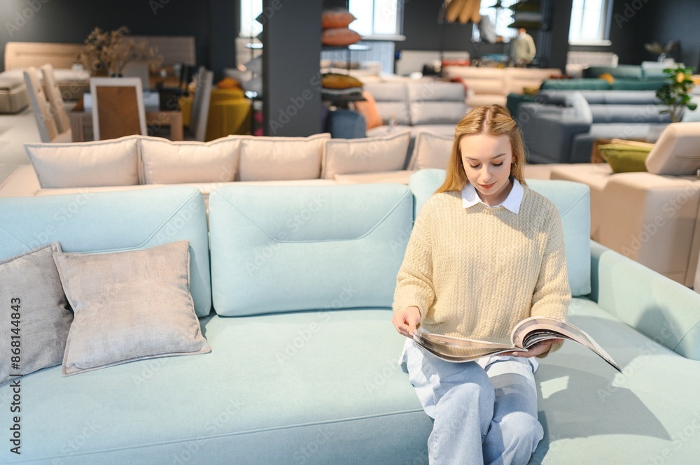 Obraz premium Happy young woman chooses sofa for home in furniture store
