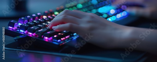 Close-up of a person's hands typing on a mechanical keyboard with vibrant RGB backlighting in a dark gaming setup.