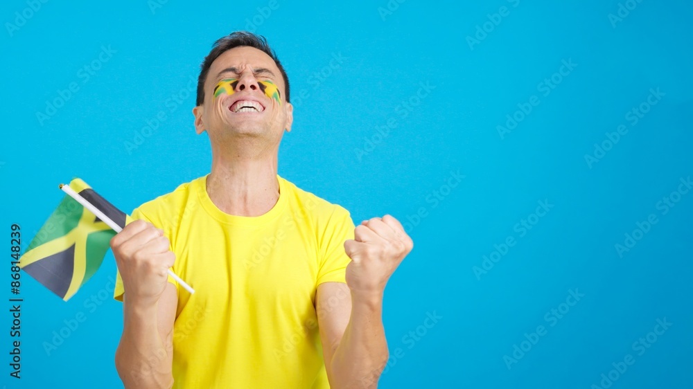 Man cheering for Jamaica screaming and waving a national flag