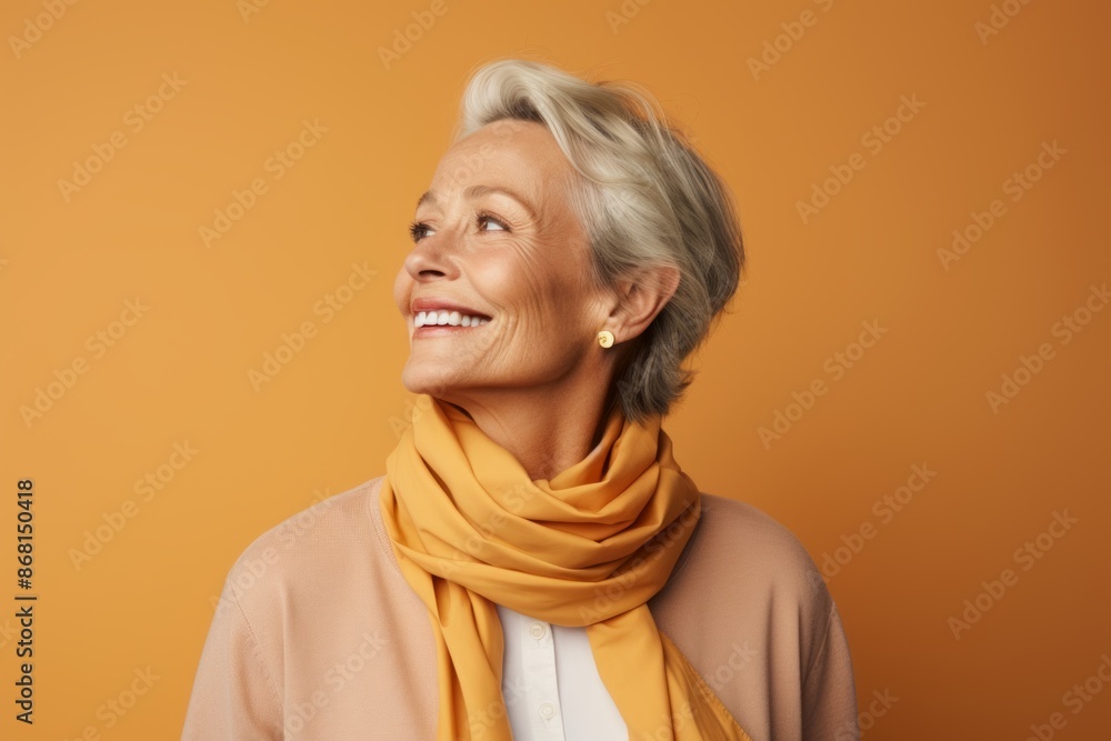 happy senior woman in yellow scarf looking up at copy space isolated on orange happy senior woman in yellow scarf looking up at copy space isolated on orange