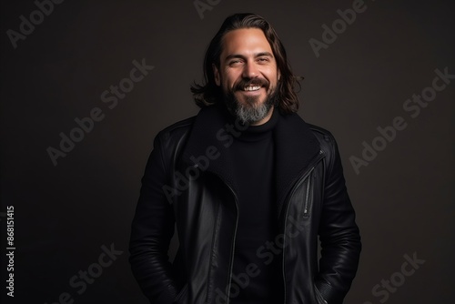 Portrait of a handsome bearded man in black leather jacket on dark background