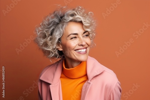 Portrait of a happy senior woman with curly hair on orange background