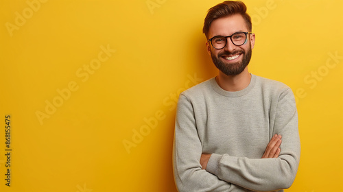 Young handsome man with beard wearing casual sweater and glasses over yellow background happy face smiling with crossed arms looking at the camera. Positive person.