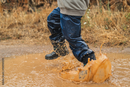 A child is splashing through a muddy puddle © Marko Domka