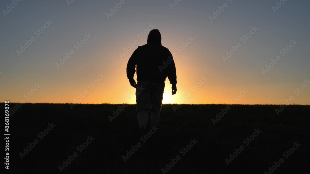 Silhouetted man hiker walking at top of hill at sunset with sun star, freedom and adventure concept, nature background Silhouetted man hiker walking at top of hill at sunset with sun star, freedom and adventure concept, nature background