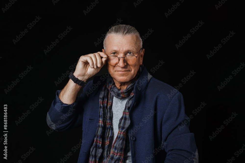 A portrait of handsome man in Blazer on dark background touching his glasses. A portrait of handsome man in Blazer on dark background touching his glasses.