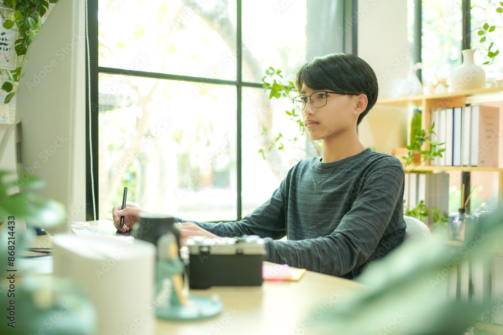 Asian teenage man using laptop for distance education and doing homework online. Young man gamer playing broadcast game on the computer for relax and rest time. Asian teenage man using laptop for distance education and doing homework online. Young man gamer playing broadcast game on the computer for relax and rest time.
