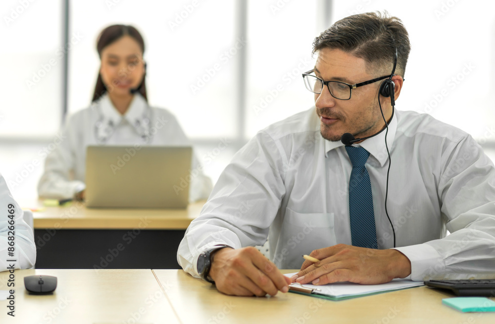 Group of happy call center smiling business operator customer help support team phone services agen working and talking with headset on desktop computer at call center office Group of happy call center smiling business operator customer help support team phone services agen working and talking with headset on desktop computer at call center office
