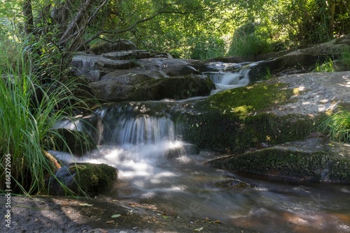 Serene Caozo waterfall flowing over moss-covered rocks in a lush forest setting in Spain