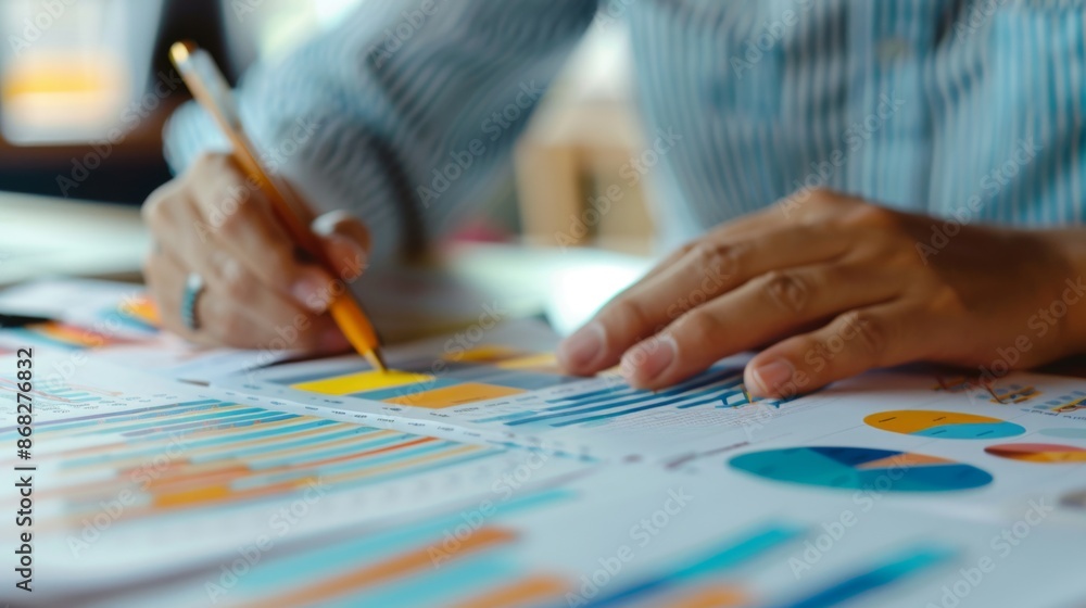 A close-up of hands working on a financial report with printed graphs and charts, highlighting detailed analysis and planning. A close-up of hands working on a financial report with printed graphs and charts, highlighting detailed analysis and planning.