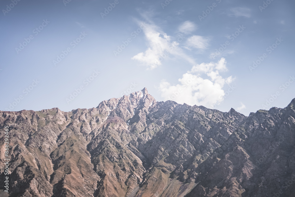 Obraz premium Rocky Tien Shan mountain range in Tajikistan in Pamir in cloudy weather in evening, colorful mountains and clouds for background