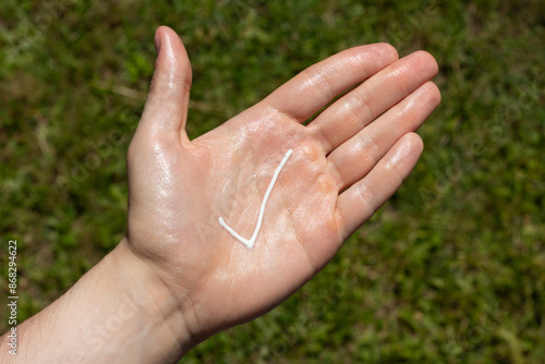 Obraz na płótnie A person applying the correct amount of sunscreen for face and neck - tick. w salonie