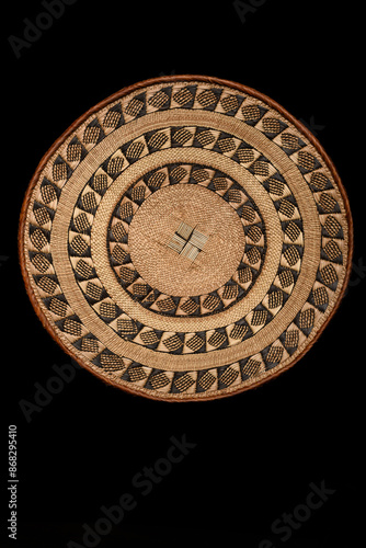 Traditional South African woven basket with geometric paterns on a black background.