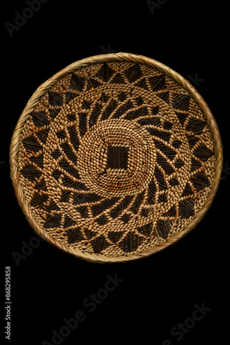 Traditional South African woven basket with geometric paterns on a black background.