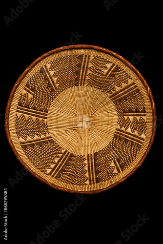 Traditional South African woven basket with geometric paterns on a black background.