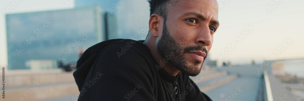 Obraz premium Young bearded male athlete standing on the embankment looking at the sea, panorama