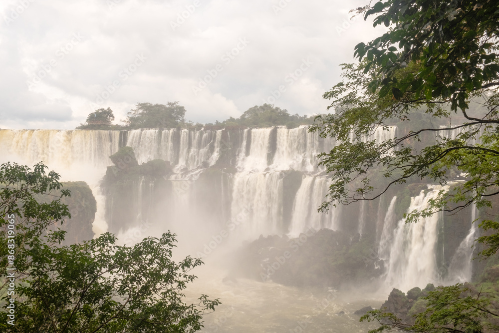 Scenic view with falls behind lush foliage and the steam of the Iguazu Falls, Argentina Scenic view with falls behind lush foliage and the steam of the Iguazu Falls, Argentina