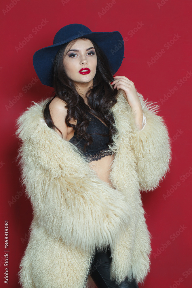 Sexy fashion model woman with long dark wavy hairstyle and red lips make-up wearing fashionable hat beauty studio portrait Sexy fashion model woman with long dark wavy hairstyle and red lips make-up wearing fashionable hat beauty studio portrait