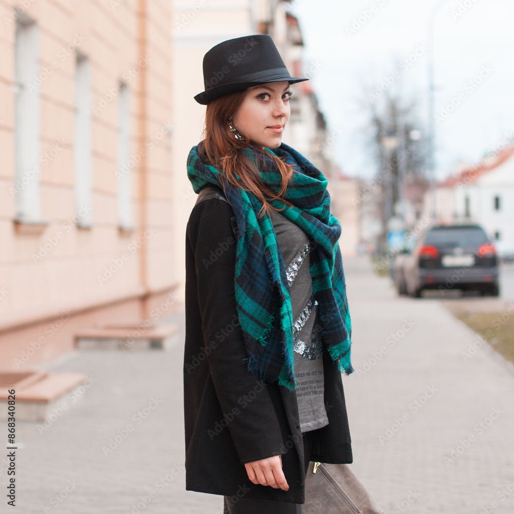urban beautiful young girl model with a hat in a black coat with a scarf walks in the city urban beautiful young girl model with a hat in a black coat with a scarf walks in the city