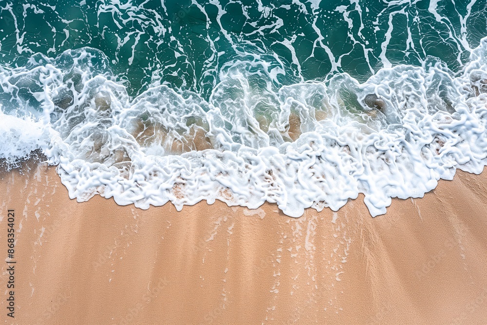 Naklejka premium Foamy ocean wave on a sandy coast line. Sunny day. Copy space. Idyllic tourism. Top view