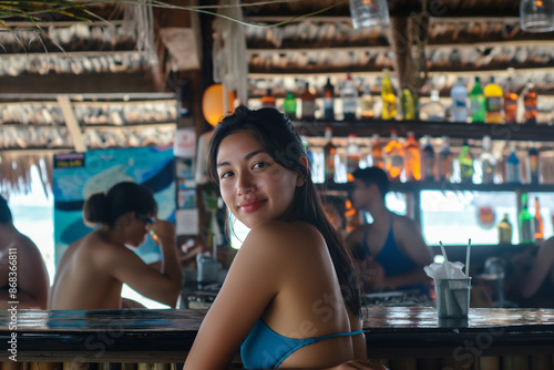 Happy woman in bikini sitting at a beach bar