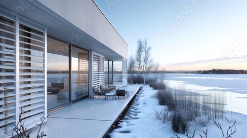 Modern villa with sleek white Bahama shutters overlooking a frozen lake, blending warmth and style